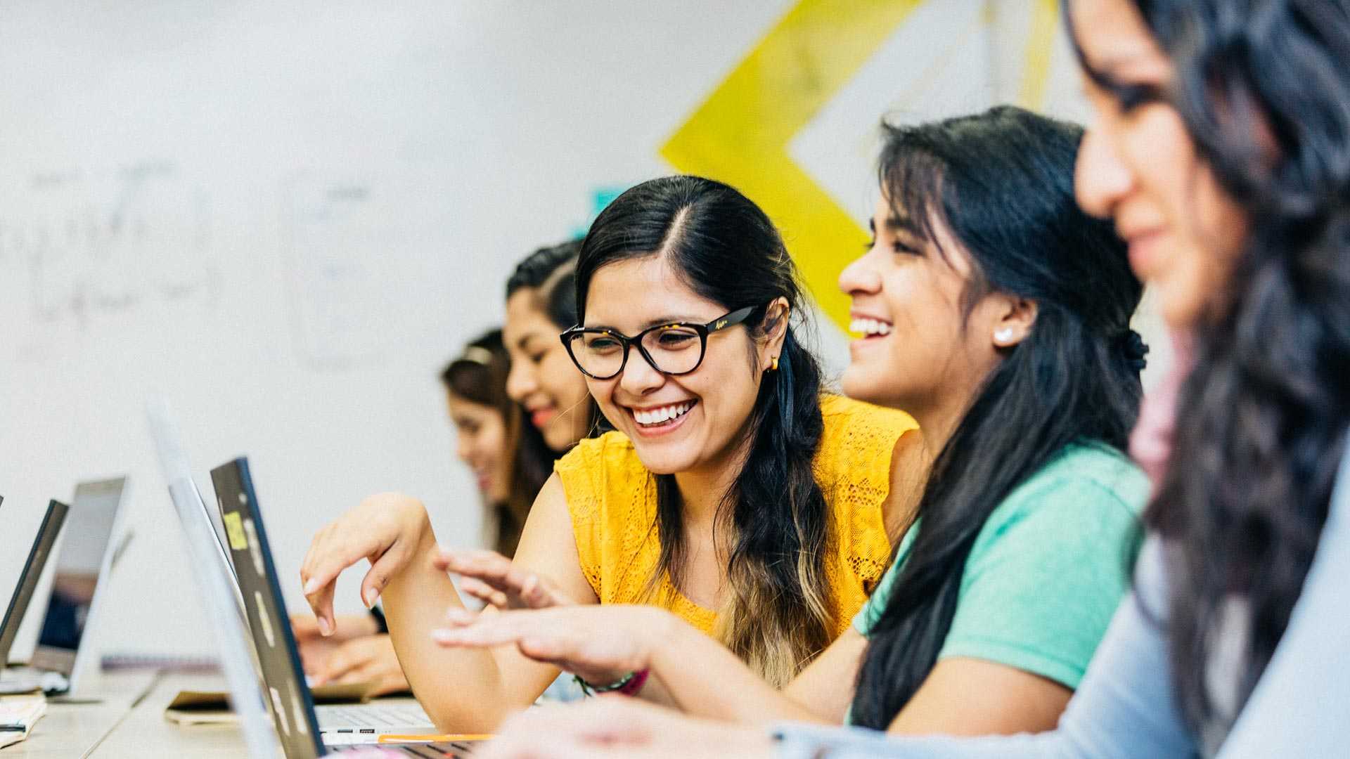 A group of women in Latin America happily working on laptops